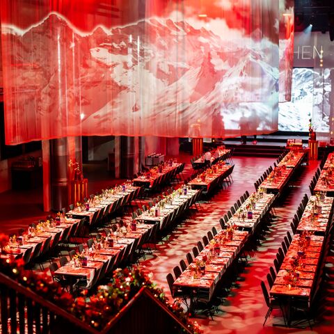 Seated hall in red lighting at a corporate Christmas party in the JED Events hall.