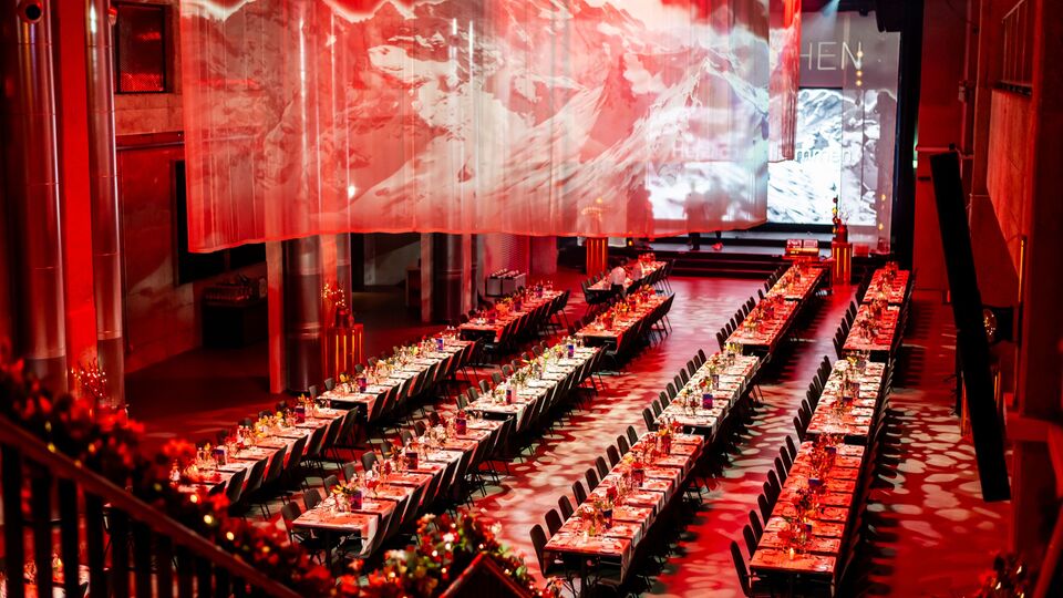Bestuhlter Saal in roter Lichtstimmung an einer Firmenweihnachtsfeier in der JED Eventhalle.