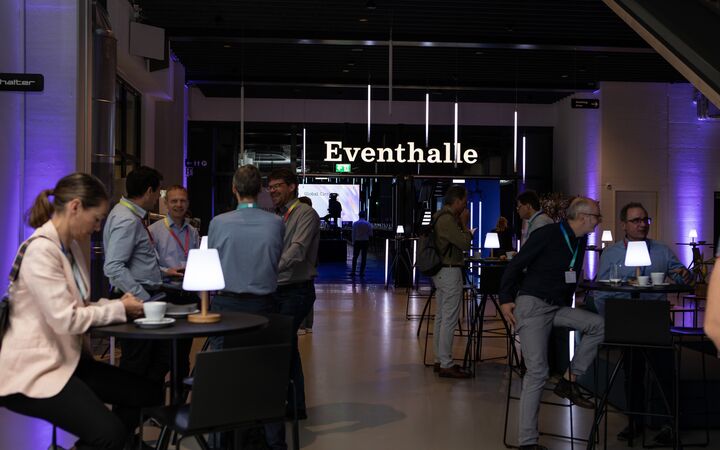 Networking an Stehtischen bei einem Kongress in der JED Eventhalle.
