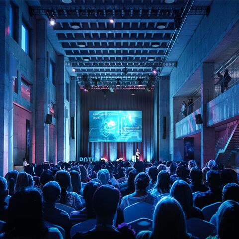 Eine Veranstaltung in der Eventhalle von JED Events mit Blick auf die Bühne mit einem grossen Screen.