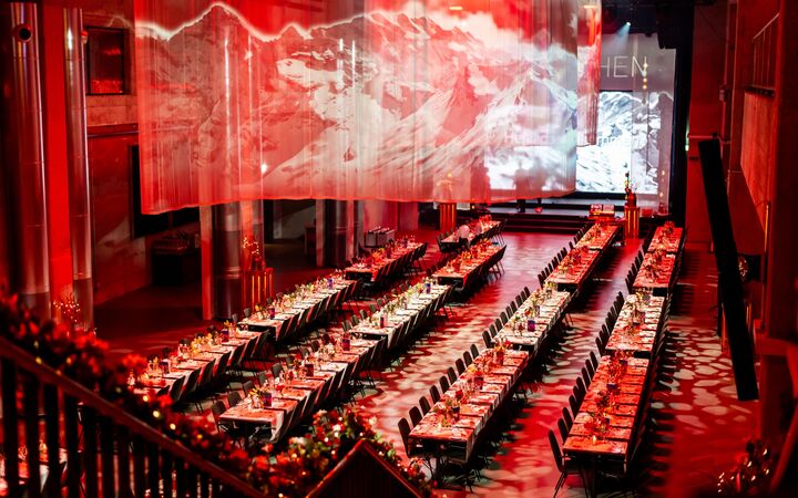 Bestuhlter Saal in roter Lichtstimmung an einer Firmenweihnachtsfeier in der JED Eventhalle.