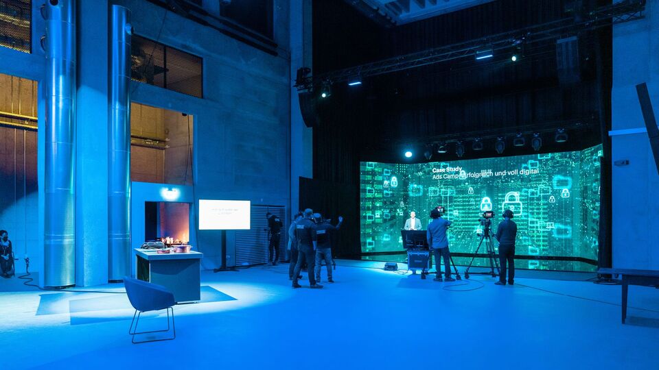 Studio-Setup mit Kamera und Leinwand für ein Streaming-Event in der JED Eventhalle.